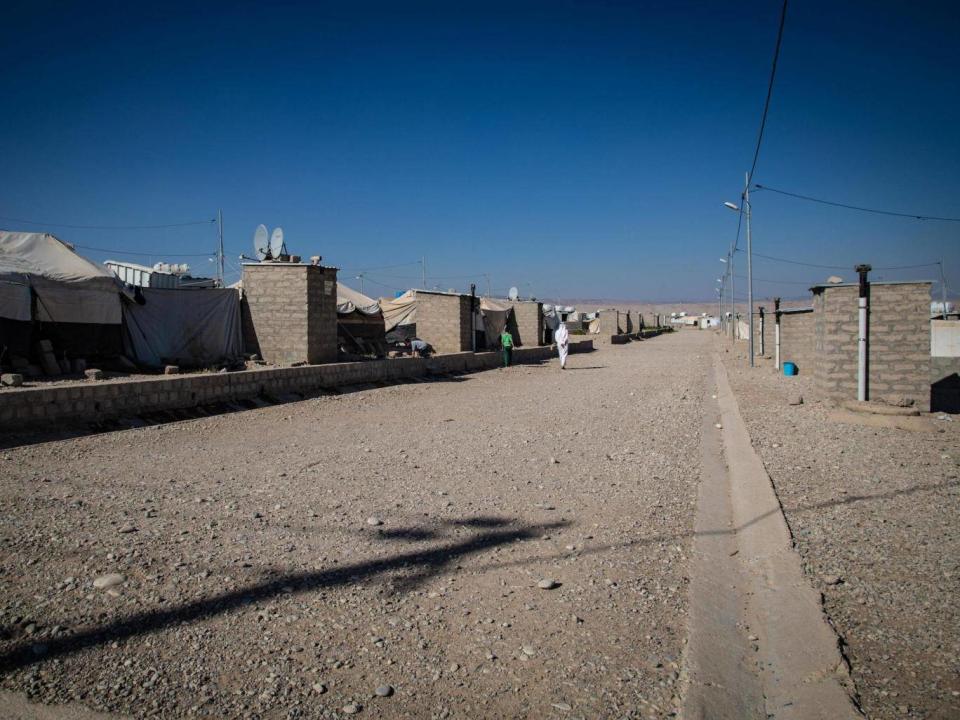 Residents of Gamawa camp walk past tents where over 100 families have lived for nearly two years since fleeing the Mosul offensive against Isis (Bel Trew)