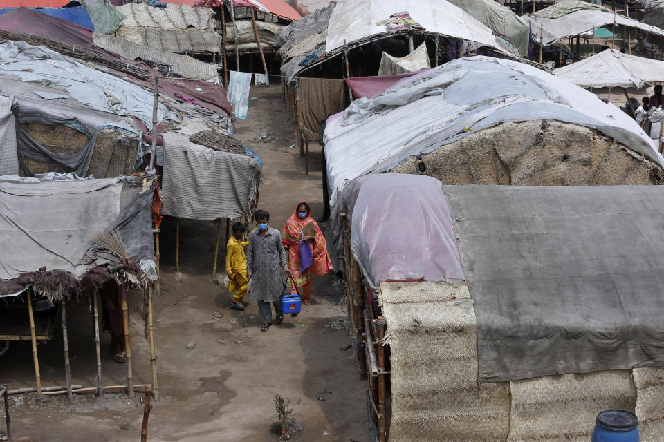 Health workers visit a slum area for polio vaccination, in Lahore, Pakistan, Saturday, Aug. 15, 2020. Pakistani government launched an anti-polio vaccination campaign in an effort to eradicate the crippling disease affected children. (AP Photo/K.M. Chaudary)