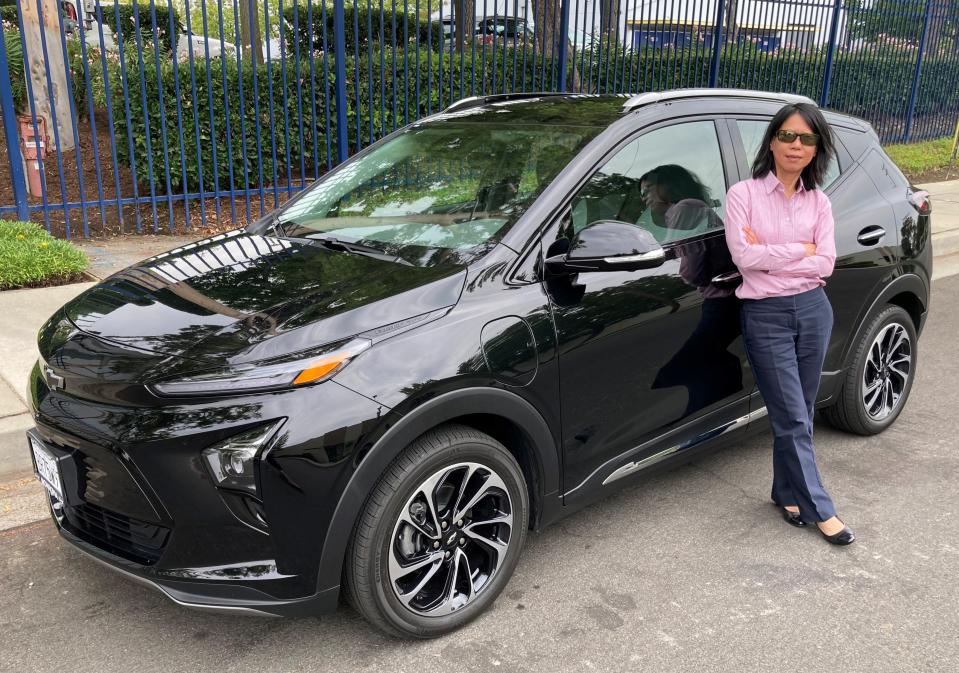 Wendy Fong of Los Angeles stands with her 2022 Bolt EUV on September 1, 2021. She bought the car new in July just before GM issued a recall on it for fire risk. Fong now wants more information on the length of the recall and GM possibly buying it back.