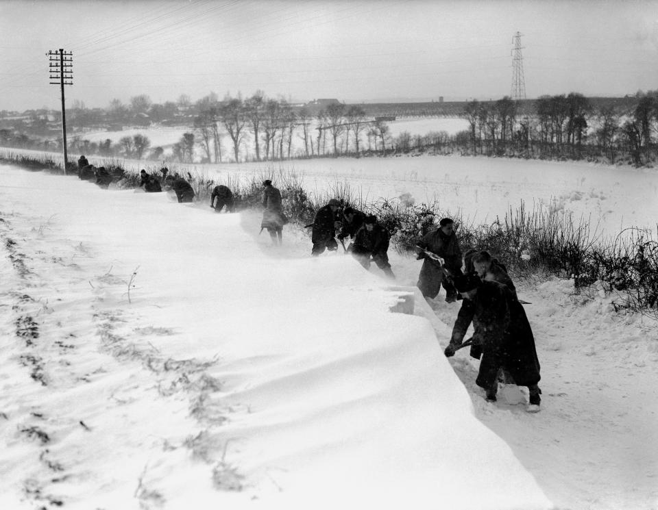 People clearing the snow in Kent which had drifted up to four feet high, blocking the road. (PA)