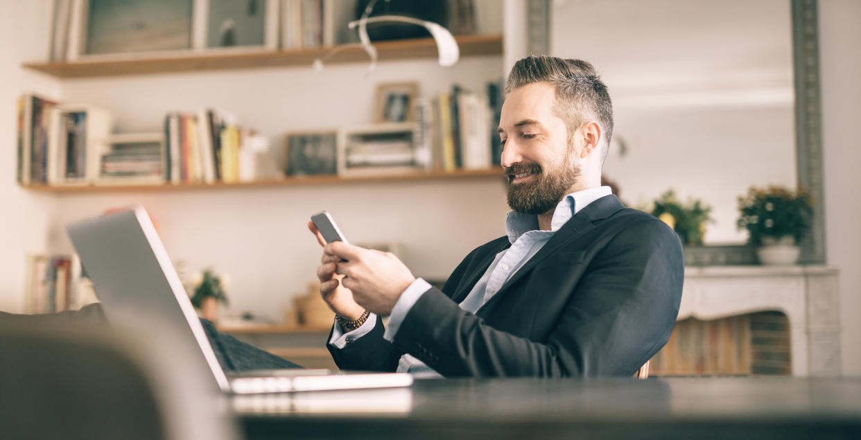 man with laptop texting at desk