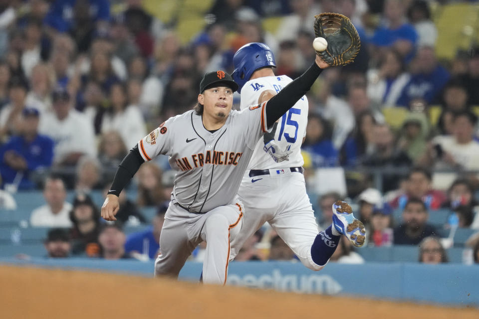 Los Angeles Dodgers' Austin Barnes (15) is safe at first ahead of a throw to San Francisco Giants first baseman Wilmer Flores (41) during the fifth inning of a baseball game in Los Angeles, Saturday, Sept. 23, 2023. (AP Photo/Ashley Landis)