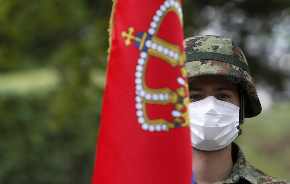 A Serbian army guard of honor with a national flag takes part in a welcoming ceremony for Serbian President Aleksandar Vucic during the vaccination at the army barracks in Belgrade, Serbia, Thursday, May 13, 2021. (AP Photo/Darko Vojinovic)