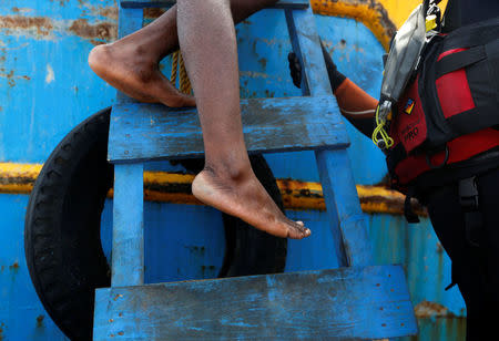 A rescued migrant climbs down from a Tunisian fishing vessel onto a rigid hulled inflatable boat (RHIB) of the Malta-based NGO Migrant Offshore Aid Station (MOAS) to be taken to the Dutch rescue ship Sea-Eye, after some 20 migrants on a rubber dinghy drowned in the central Mediterranean in international waters off the coast of Libya, April 16, 2017. REUTERS/Darrin Zammit Lupi