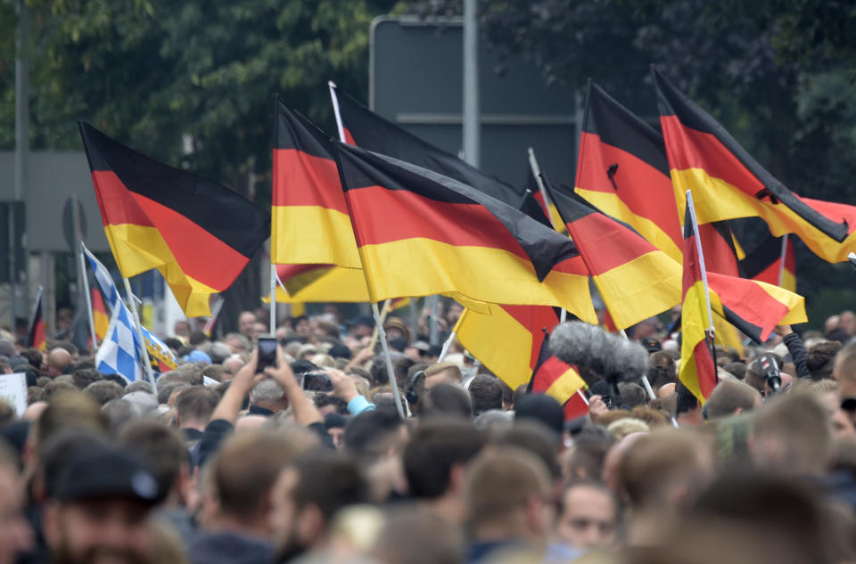 Demonstrators carry German flags during a demonstration in Chemnitz, eastern Germany, Saturday, Sept. 1, 2018, after several nationalist groups called for marches protesting the killing of a German man last week, allegedly by migrants from Syria and Iraq. (AP Photo/Jens Meyer)