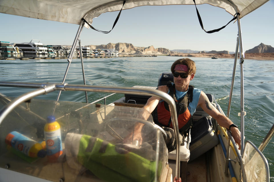 Utah State University master's student Barrett Friesen steers a boat through Lake Powell on Tuesday, June 7, 2022 in Page, Ariz. The student and colleagues are on a mission to save the humpback chub, an ancient fish under assault from nonnative predators in the Colorado River. (AP Photo/Brittany Peterson)