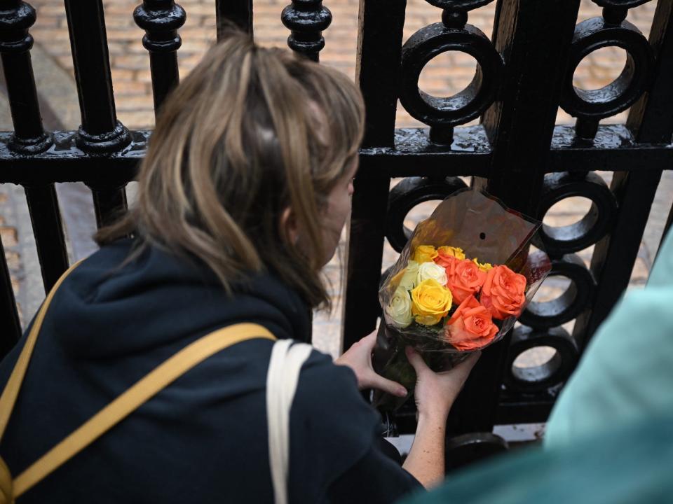 A woman lays flowers in Queen Elizabeth II's honor at Buckingham palace.