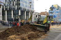 A farmer uses his tractor to dump manure and hay on a main boulevard near the European Council building in Brussels, Tuesday, March 26, 2024. Dozens of tractors sealed off streets close to European Union headquarters where the 27 EU farm ministers are meeting to discuss the crisis in the sector which has led to months of demonstrations across the bloc. (AP Photo/Geert Vanden Wijngaert)