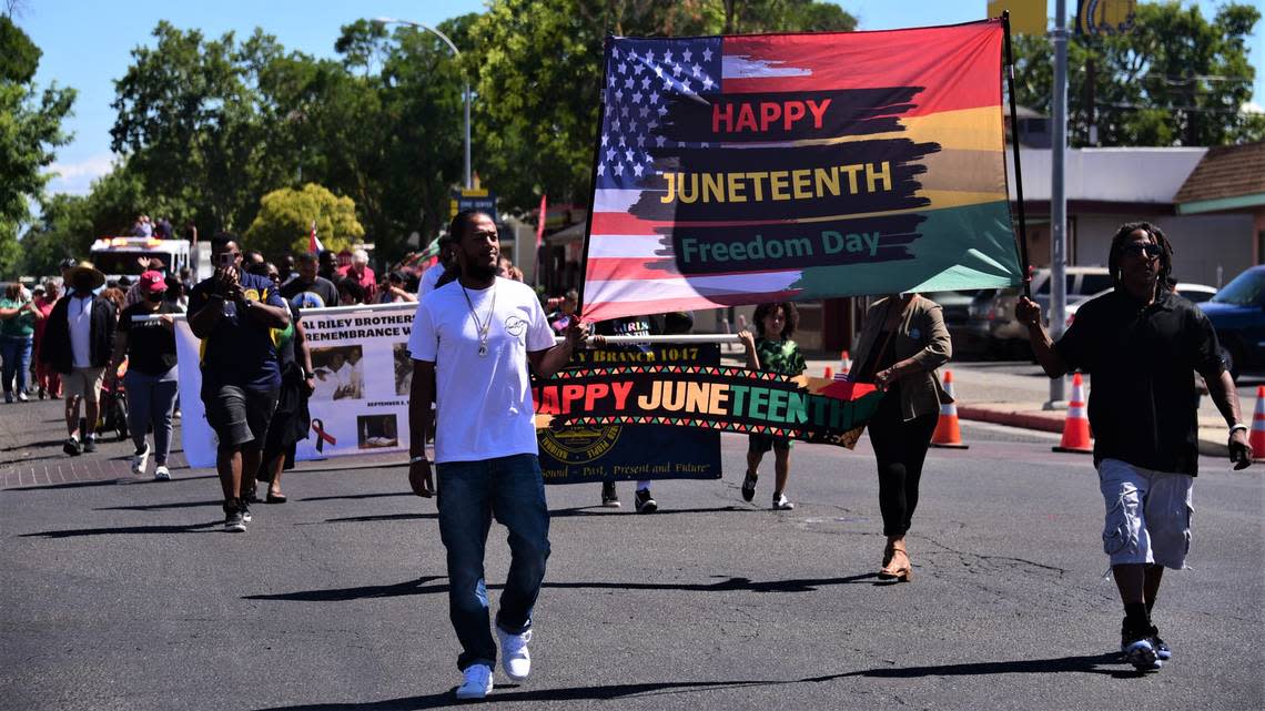 Lonnie Pierce, left, and his father Roscoe Pierce hold a Happy Juneteenth flag during the first Juneteenth Parade in Merced, Calif. on Saturday, June 18, 2022.