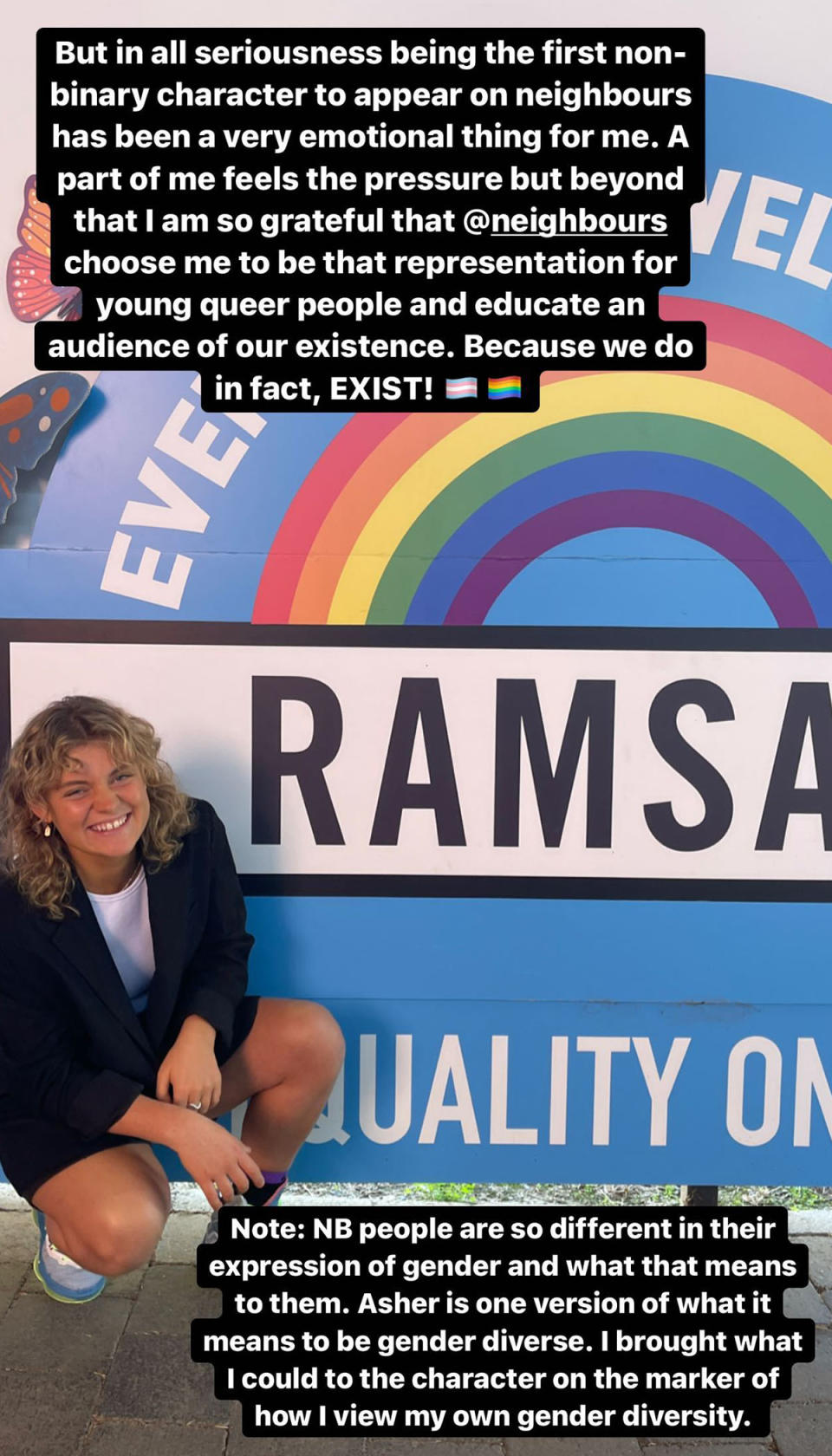 Kathleen Ebbs poses next to a Ramsay Street sign with a rainbow. 