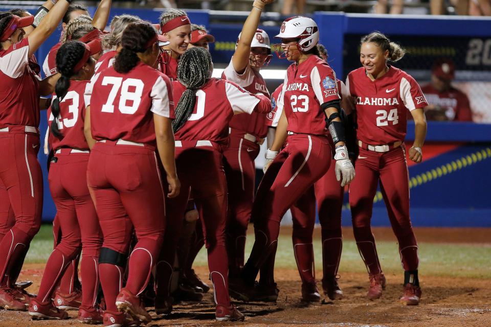 OU's Tiare Jennings (23) is greeted at home after hitting a home run in the fifth inning of a 16-1 win against Texas on Wednesday in Game 1 of the WCWS finalsat USA Softball Hall of Fame Stadium.