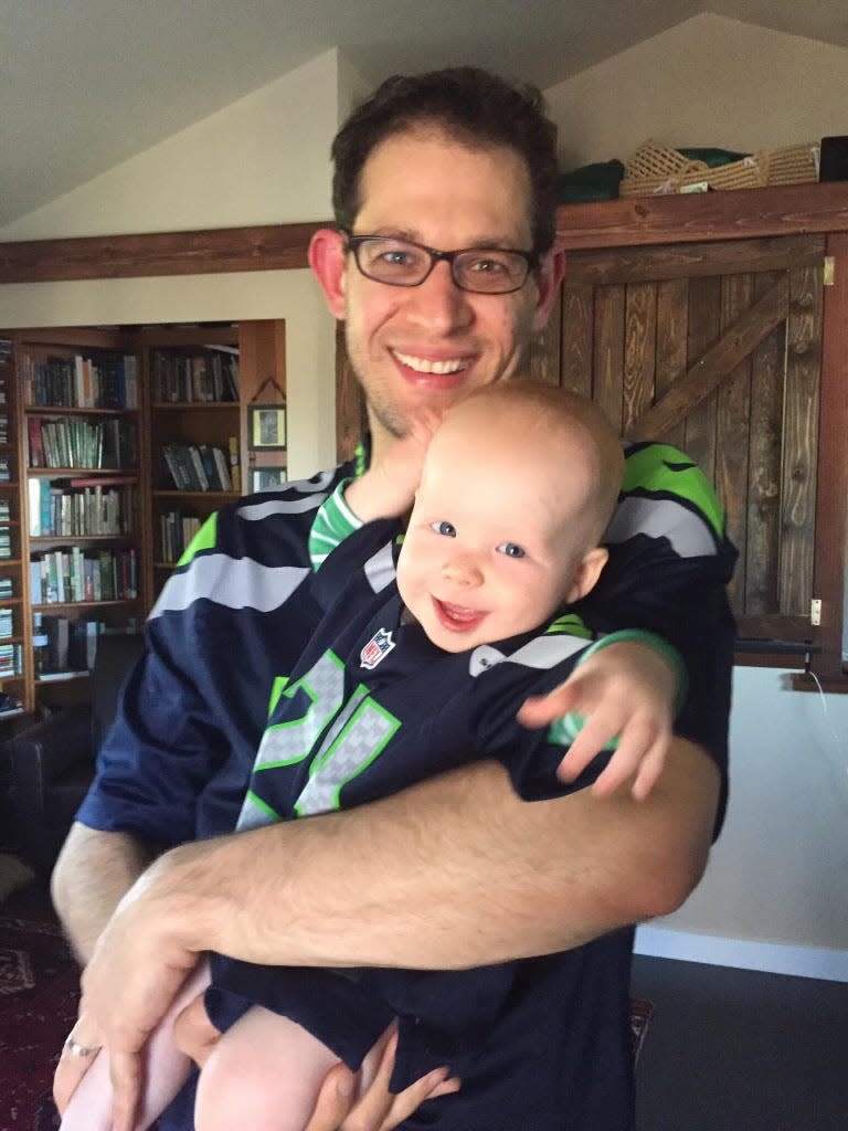 Dad posing with baby in football gear