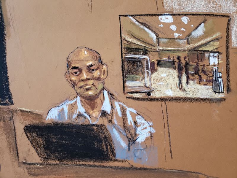 Hotel worker Rothschild Capulong testifies under a photo of the lobby of the DoubleTree Hotel in New York Criminal Court