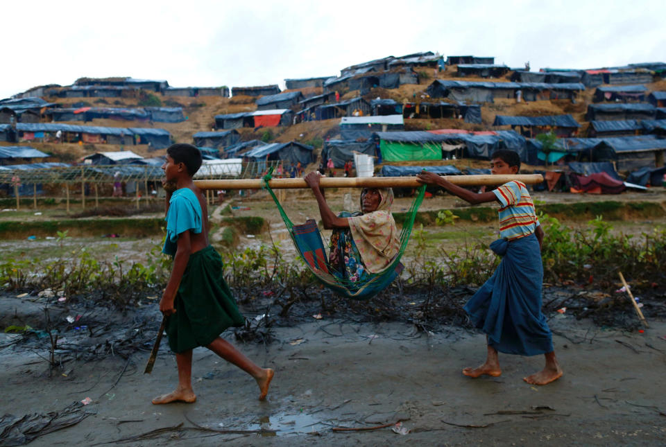 Rohingya refugee children carry an old woman in a sling near the Balukhali makeshift refugee camp in Cox's Bazar, Bangladesh, on Sept. 13, 2017.