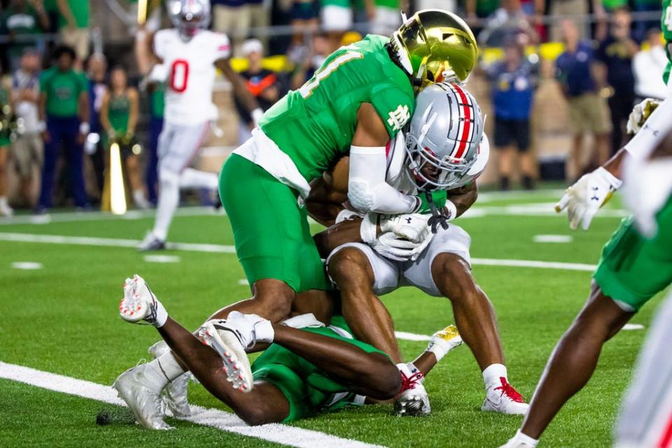 Notre Dame safety Ramon Henderson, left, and cornerback Cam Hart, bottom, stop Ohio State receiver Emeka Egbuka at the goal line late in the fourth quarter of an NCAA college football game Saturday, Sept. 23, 2023, in South Bend, Ind. (AP Photo/Michael Caterina)