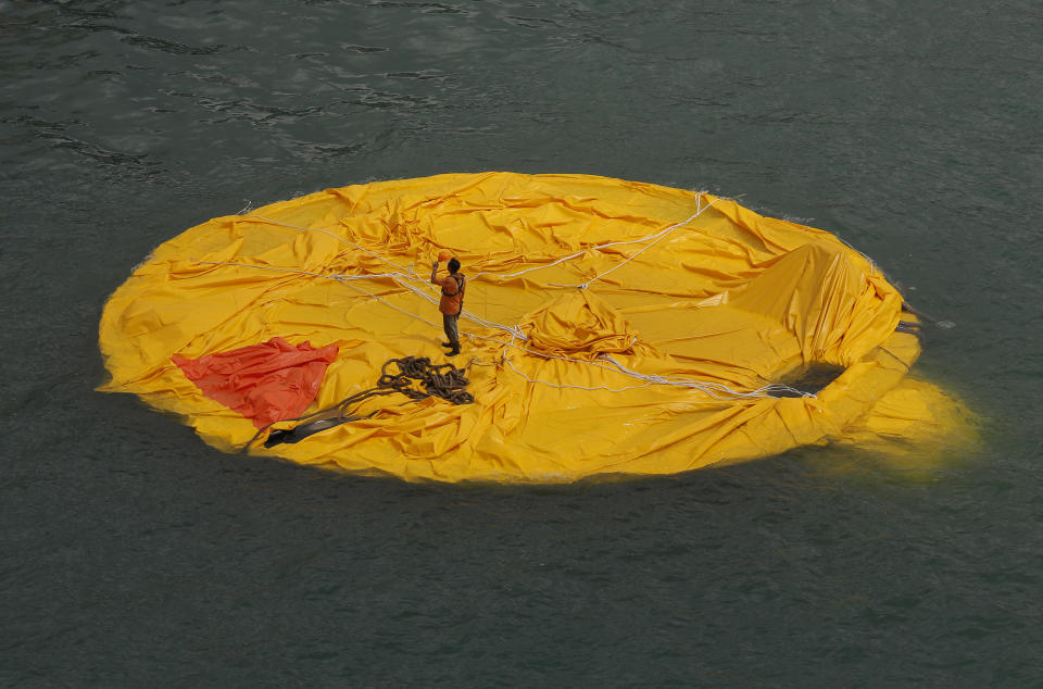 A worker stands on a deflated rubber duck created by Dutch artist Florentijn Hofman in Hong Kong's Victoria Harbor Wednesday, May 15, 2013. The 16.5-meter (54-foot)-tall inflatable rubber duck which attracted visitors to the harbor, has been deflated since Tuesday evening. (AP Photo/Vincent Yu)