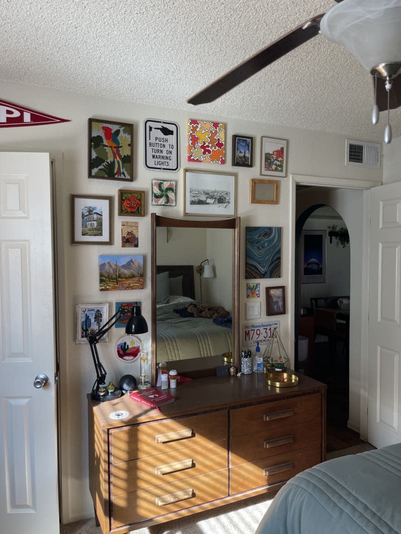 A gallery wall of decorative pieces including a license plate above a wooden dresser with attached mirror.