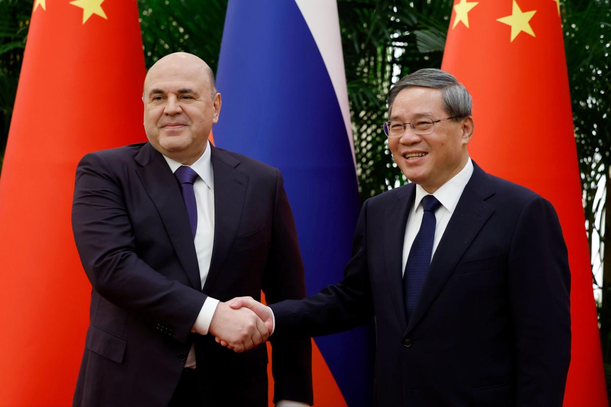 Russian Prime Minister Mikhail Mishustin, left, and Chinese Premier Li Qiang shake hands in Beijing this morning (AP)