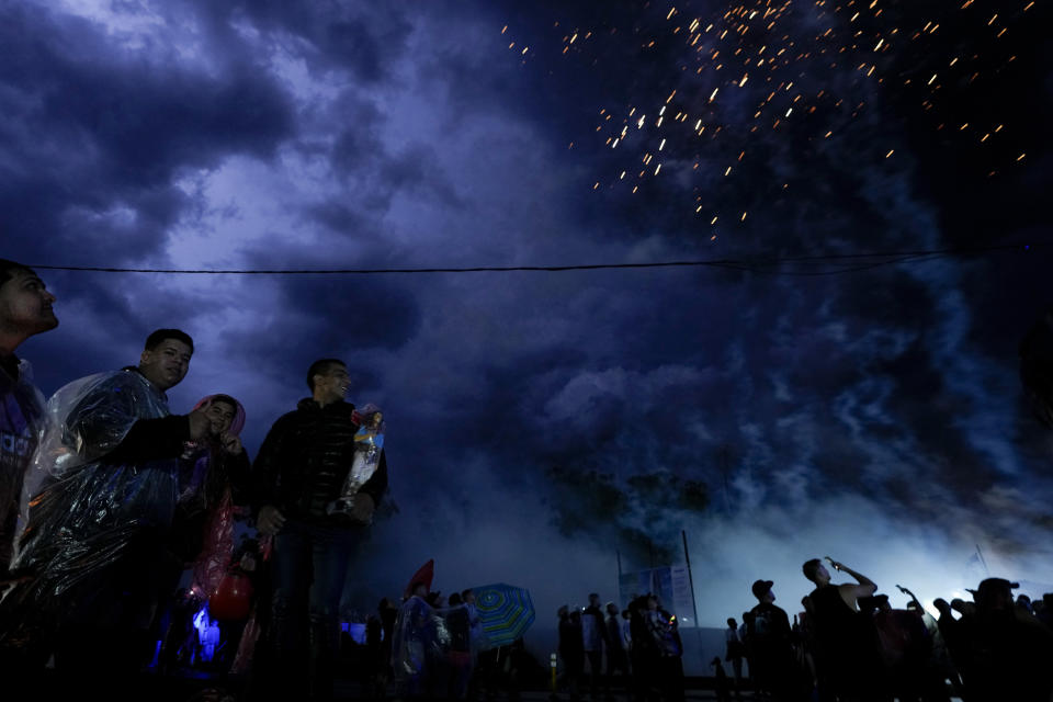 Varias personas miran los fuegos artificiales, en medio de la lluvia, en el santuario dedicado al santo pagano argentino Gauchito Gil en Mercedes, Corrientes, Argentina, el domingo 7 de enero de 2024. Cada 8 de enero, devotos de todo el país visitan ese espacio para pedir o agradecerle por milagros. (AP Foto/Natacha Pisarenko)