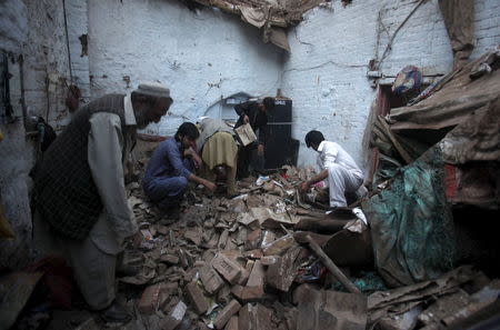 Residents search for belongings in the rubble of a house after it was damaged by an earthquake in Peshawar, Pakistan, October 26, 2015. REUTERS/Fayaz Aziz