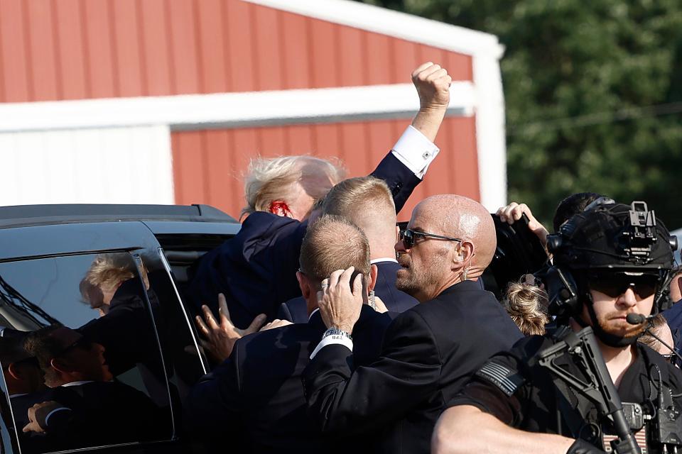 Republican presidential candidate former President Donald Trump pumps his fist as he is rushed into car after an incident at a rally on July 13, 2024 in Butler, Pennsylvania.