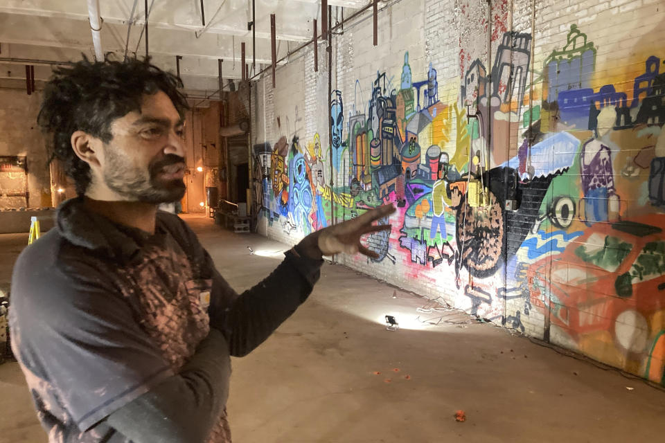 Alex Smith of Minneapolis, who goes by the tag "Shock" in his painting, describes a graffiti history of the former Pillsbury Mills plant, Nov. 9, 2023, in Springfield, Ill. Walls of mill buildings were given to Shock and other artists for "Visitors Art Exhibits" in November. The mill operated under Minneapolis-based Pillsbury and another owner for 71 years but has been vacant nearly a quarter-century. (AP Photo/John O'Connor)