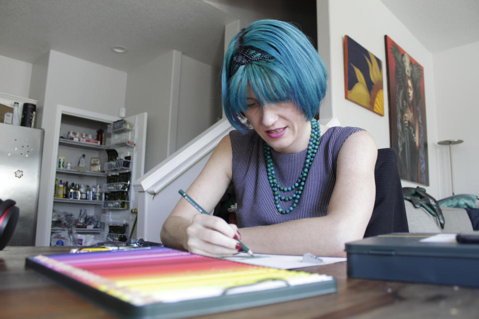 Lynn Hunt, who took out between $45,000 and $50,000 in student loans and was a Pell Grant recipient, uses colored pencil to fill in a sketch at Hunt's home in Beaverton, Ore. on Wednesday, Aug. 24, 2022. Hunt says President Biden's student loan forgiveness plan isn't enough to help because Hunt owes about $70,000 due to a 6.7% interest rate on the loans. Hunt says the temporary moratorium on loan repayment during the COVID-19 pandemic allowed Hunt to stop working 80-hour weeks and to return to artistic hobbies. (AP Photo/Gillian Flaccus)