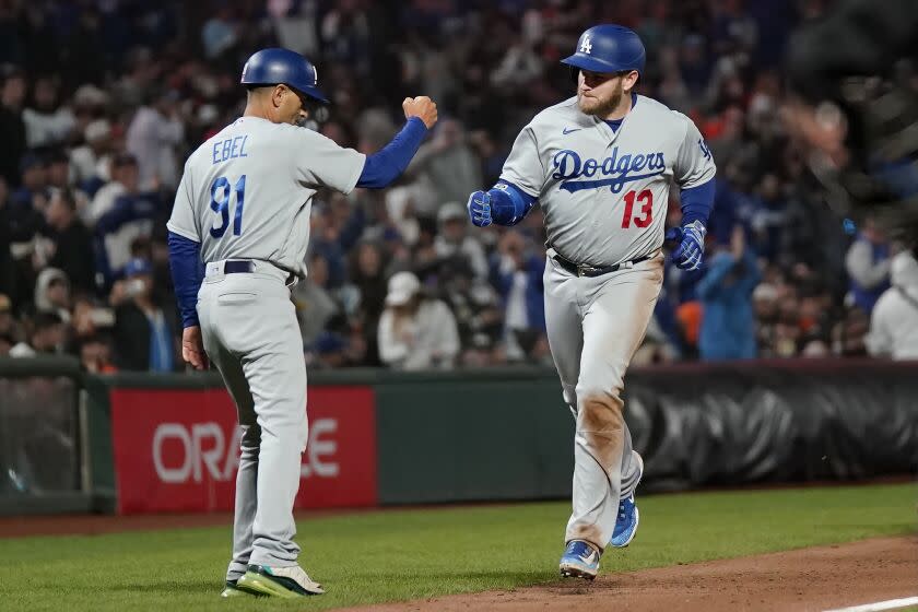 Los Angeles Dodgers' Max Muncy (13) is congratulated by third base coach Dino Ebel (91) after hitting a grand slam.