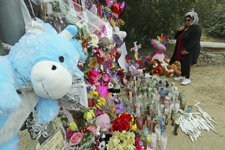 A woman crosses herself at a large memorial to Trinity Love Jones, the 9-year-old girl whose body was found in a duffel bag along a suburban Los Angeles equestrian trail in Hacienda Heights, Calif., Monday, March 11, 2019. Two people have been detained in connection with the case. The discovery happened last week. (AP Photo/Reed Saxon)