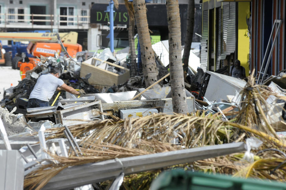 A man hauls debris away from a pizza restaurant that was badly damaged by Hurricane Ian at Fort Myers Beach, Fla., on Sunday, Oct. 9, 2022. (AP Photo/Jay Reeves)