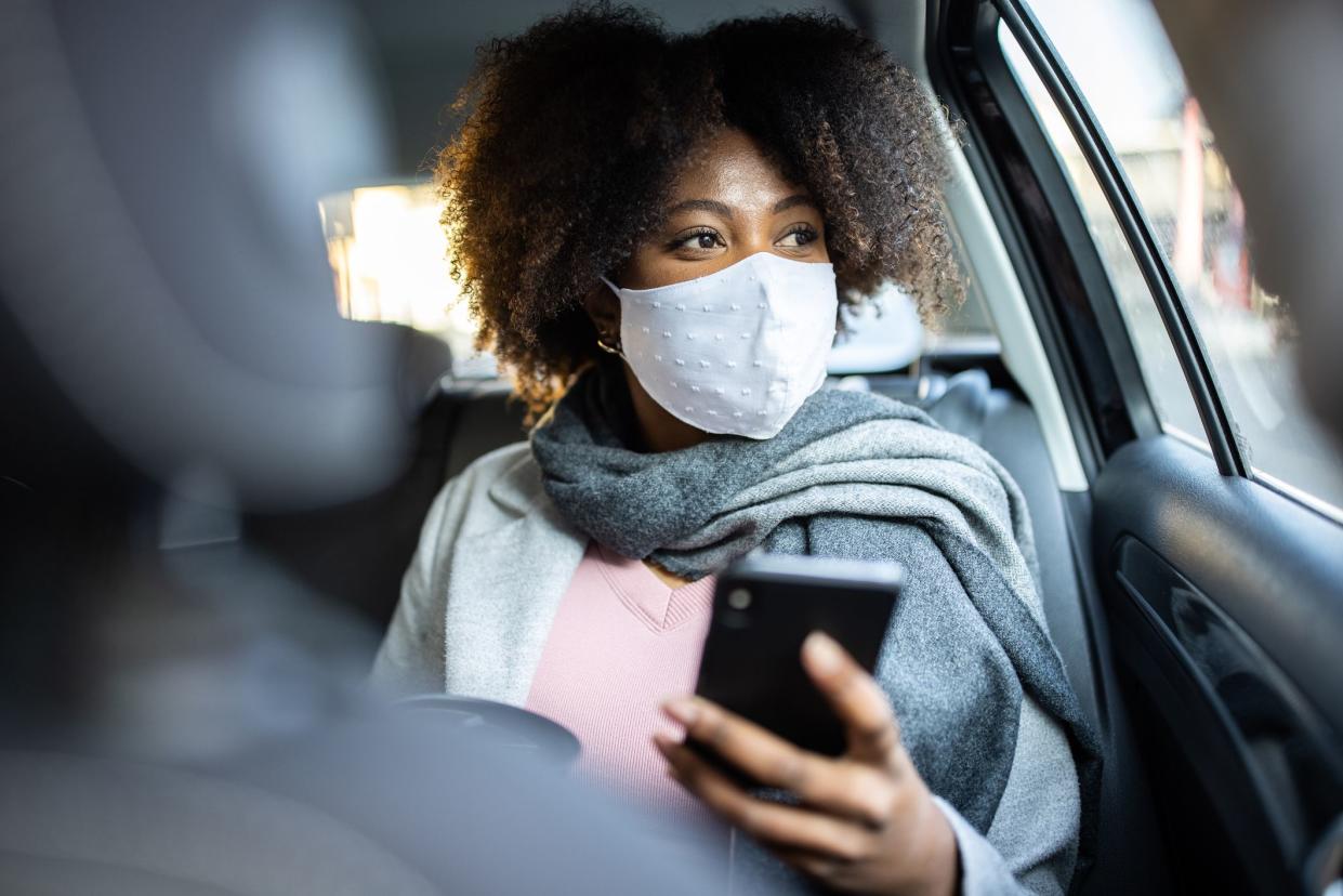 Mixed race woman with protective face mask travel by taxi. Businesswoman traveling by taxi during COVID-19 pandemic.