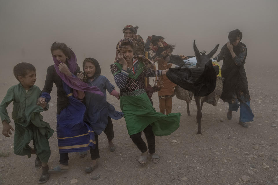 FILE - Afghan girls and women carry donated aid to their tents, while they are scared and crying from the fierce sandstorm, after an earthquake in Zenda Jan district in Herat province, western of Afghanistan, Oct. 12, 2023. Almost 100,000 children direly need support three months after earthquakes devastated western Afghanistan, the U.N. children’s agency said Monday, Jan. 15, 2024. (AP Photo/Ebrahim Noroozi, File)