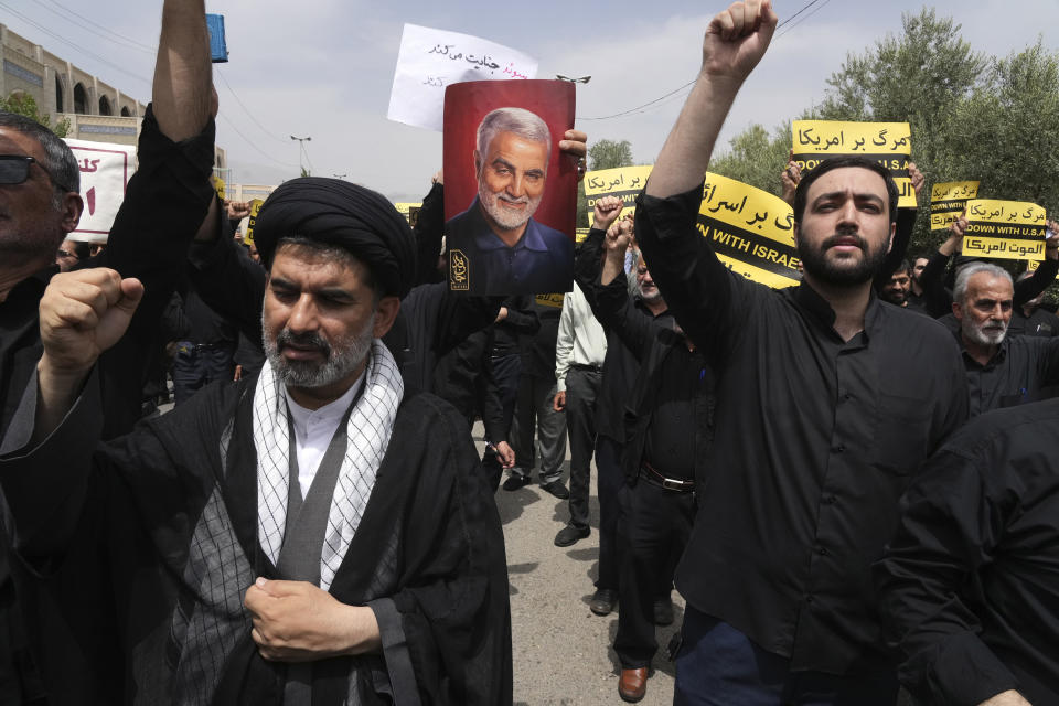 Iranian worshippers chant slogans as one of them holds a poster of the late Revolutionary Guard Gen. Qassem Soleimani, who was killed in a U.S. drone attack in 2020, in a protest against Sweden after the Nordic nation allowed an Iraqi man insult the Muslim holy book, the Quran, after their Friday prayers in Tehran, Iran, Friday, July 21, 2023. (AP Photo/Vahid Salemi)