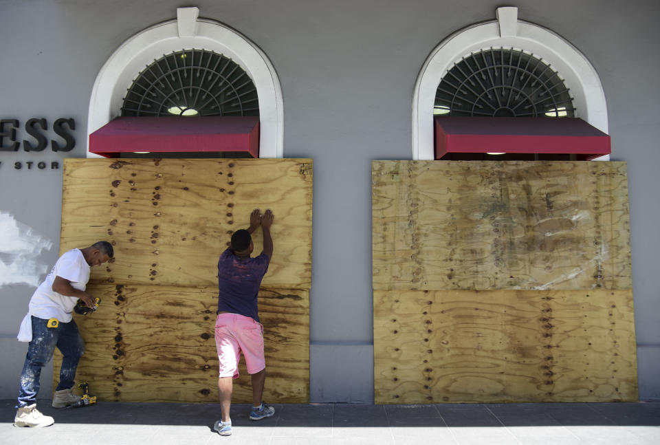 Workers cover shop windows with wood in preparation for protests against Gov. Ricardo Rosselló near La Fortaleza in San Juan, Puerto Rico, Wednesday, July 17, 2019. Protesters are demanding Rosselló step down for his involvement in a private chat in which he used profanities to describe an ex-New York City councilwoman and a federal control board overseeing the island's finance. (AP Photo/Carlos Giusti)