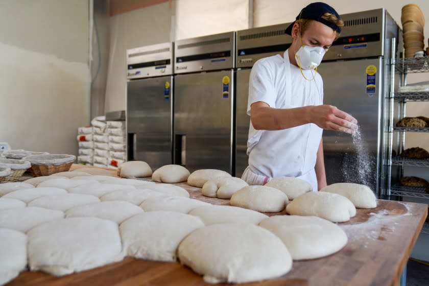 Jyan Isaac sprinkles flour on dough as he works in his kitchen at his Culver City shop.