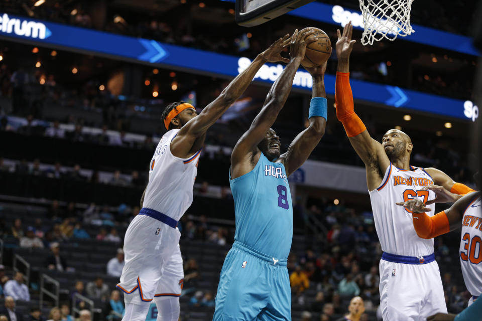 Charlotte Hornets center Bismack Biyombo, center, goes up for a dunk between New York Knicks forward Maurice Harkless, left, and center Taj Gibson during the first half of an NBA basketball game in Charlotte, N.C., Wednesday, Feb. 26, 2020. (AP Photo/Nell Redmond)