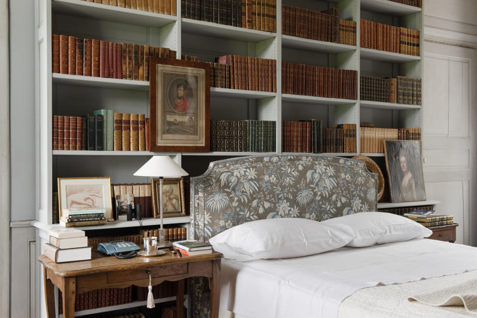 Bookshelves above a bed with a Marvic fabric headboard