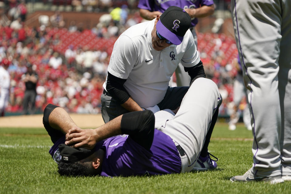 Colorado Rockies starting pitcher Antonio Senzatela is checked on by a trainer after being injured while covering first base during the second inning of a baseball game against the St. Louis Cardinals Thursday, Aug. 18, 2022, in St. Louis. Senzatela left the game. (AP Photo/Jeff Roberson)