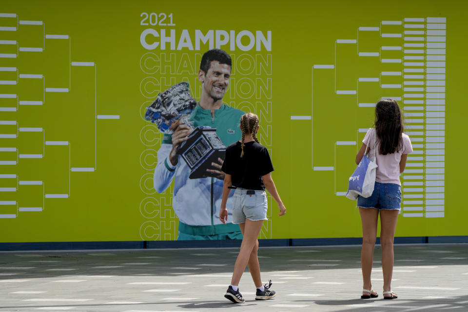 FILE - Visitors stop to take a photo of a billboard featuring defending champion Serbia's Novak Djokovic ahead of the Australian Open at Melbourne Park in Melbourne, Australia, Tuesday, Jan. 11, 2022. The drama over Djokovic's ability to defend his Australian Open title without a COVID-19 vaccine has sparked fierce public debate, but there’s little sign it threatens his multimillion-dollar sponsorship deals. It's unclear if the No. 1 seed can compete Monday, Jan. 17 after Australian officials revoked his visa for a second time. (AP Photo/Mark Baker)