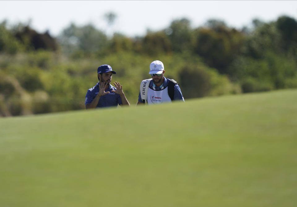 Abraham Ancer, of Mexico, left, speaks with his caddie as they walk on the third fairway during the first round of the Hero World Challenge PGA Tour at the Albany Golf Club, in New Providence, Bahamas, Thursday, Dec. 2, 2021.(AP Photo/Fernando Llano)