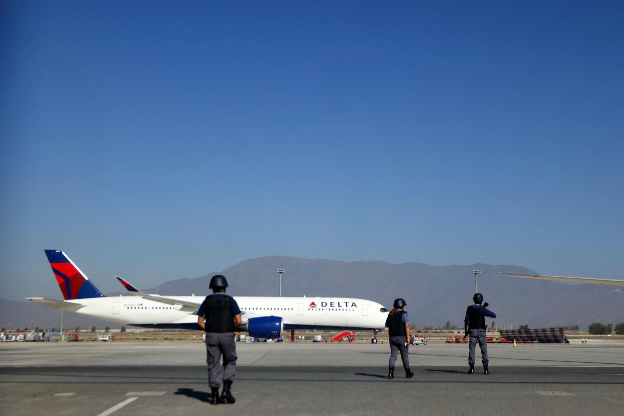Several police officers stand in front of a Delta airlines plane following a shootout at an airport in Chile.