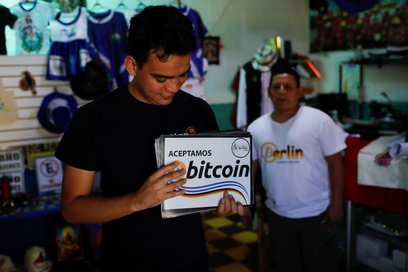 Gerardo Linares, miembro de una comunidad Bitcoin, sostiene carteles recién impresos para colocar en nuevos negocios que aceptarán Bitcoin, en Berlín, El Salvador