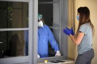 In this photo taken on Friday, May 8, 2020, internal medicine Konstantinos Kyriakoulis, left, stands in the window of the patient's room as he speaks with MSc student at Athens University (EKPA) Maria Adami, at the COVID-19 Clinic of Sotiria Hospital in Athens. Greece's main hospital for the treatment of COVID-19 is also the focus of a hands-on training program for dozens of medical students who volunteered to relieve hard-pressed doctors from their simpler duties while gaining a close peek at the front lines of a struggle unmatched in modern medical history. (AP Photo/Thanassis Stavrakis)