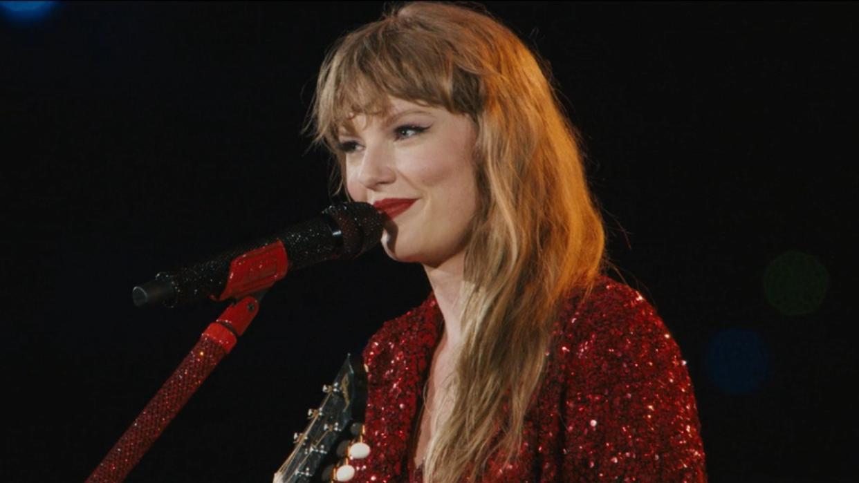  A screenshot of Taylor Swift smiling while singing All Too Well during the Eras Tour. 