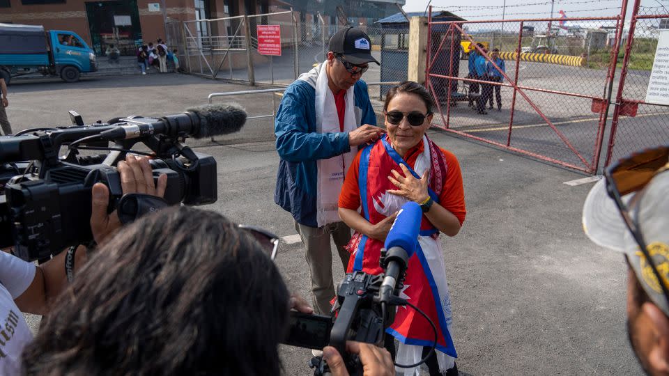 Kim Lal Gautam places the Nepali flag on Phunjo Lama on her arrival at the airport in Kathmandu. - Niranjan Shrestha/AP