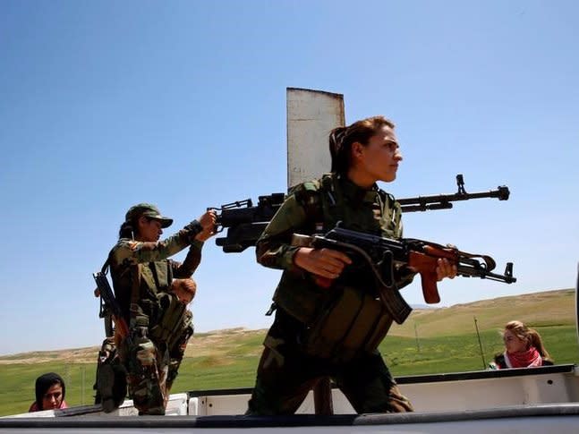 Yazidi female fighter Asema Dahir (L), 21, holds a weapon as she rides a pickup truck during a deployment near the frontline of the fight against Islamic State militants in Nawaran near Mosul, Iraq, April 20, 2016.  REUTERS/Ahmed Jadallah
