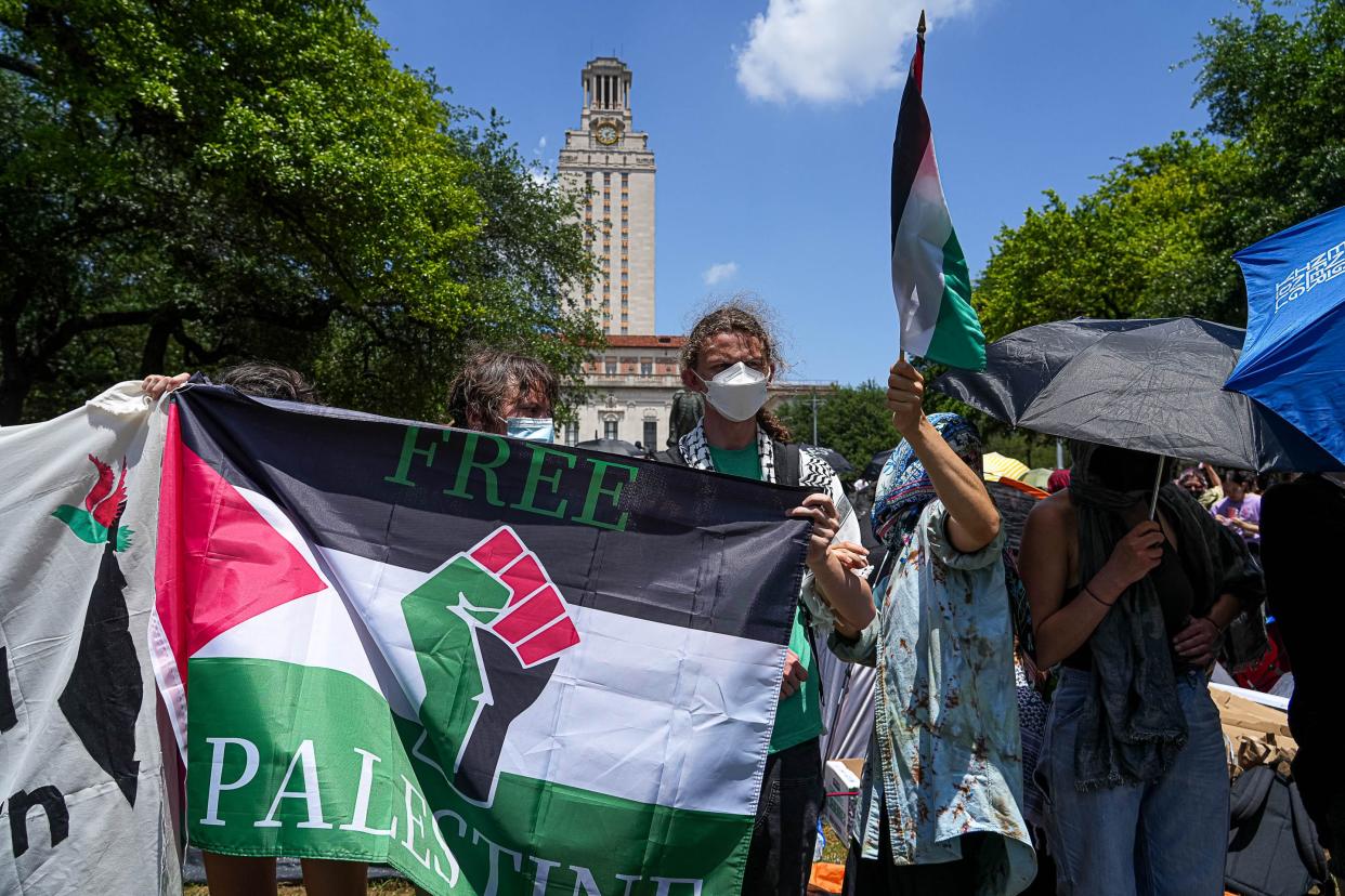 Protesters hold signs and flags last week at an encampment on the University of Texas' South Mall to call attention to the war in Gaza and to condemn UT’s relationship with defense companies.