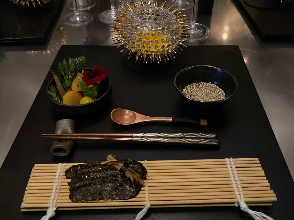 a black stone with bamboo rolling matt, seaweed, rice, and bowls