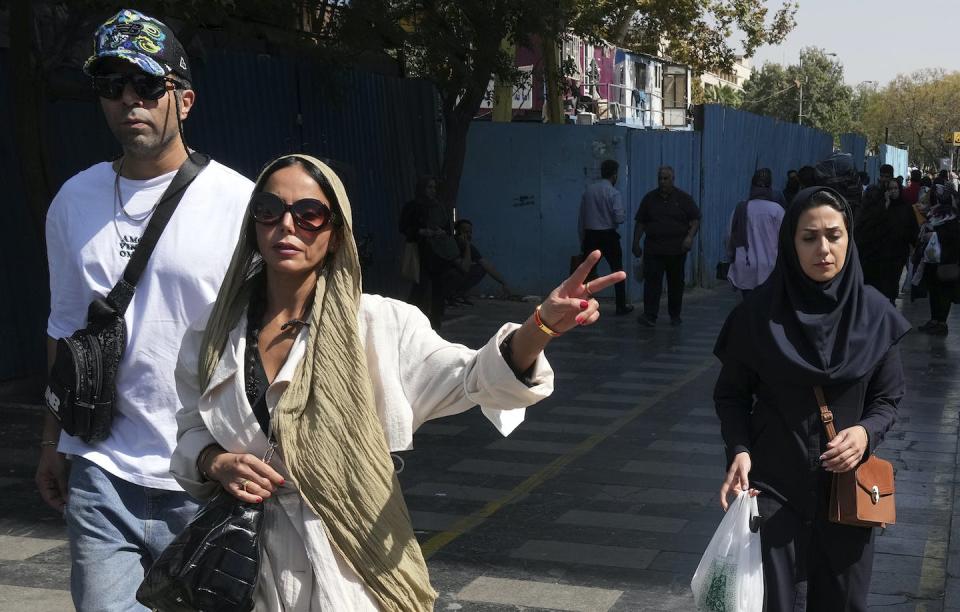 A woman flashes a victory sign as she walks around in the old main bazaar of Tehran, Iran, in October 2022. (AP Photo/Vahid Salemi)