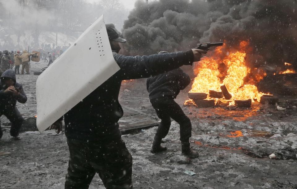 FILE - In this Wednesday, Jan. 22, 2014 file photo a protester points a handgun during a clash with police in central Kiev, Ukraine. After two months of anti-government protests, modern Ukraine has never been so bitterly polarized. To be sure, Ukraine has long been divided. Russia and Europe have vied for dominance for centuries, causing deep cultural differences between the mostly Ukrainian-speaking western and central regions on the one hand, and the Russian-speaking east and south on the other. But as the crisis has deepened, each side has grown stronger in its convictions, and those who stood in the middle have been forced to choose sides. (AP Photo/Efrem Lukatsky, file)